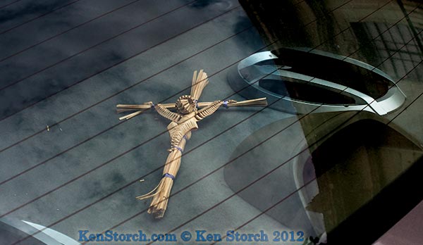 Straw crucifix behind rear car-window antenna